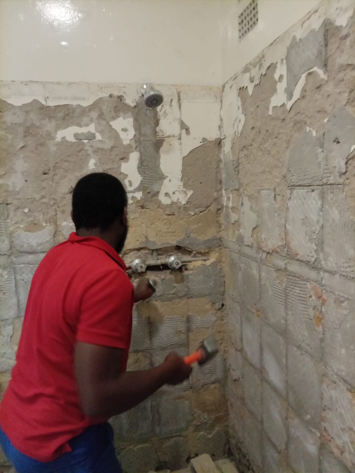 Technician stripping tiles during a shower renovation